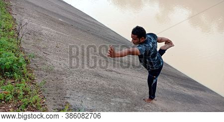 District Katni, India - September 02, 2019: An Indian Boy Doing Yogasana On Water Canal Cemented Bac