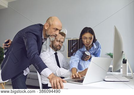 Group Of Colleagues Or Partners Looking At Laptop Screen And Discussing New Project
