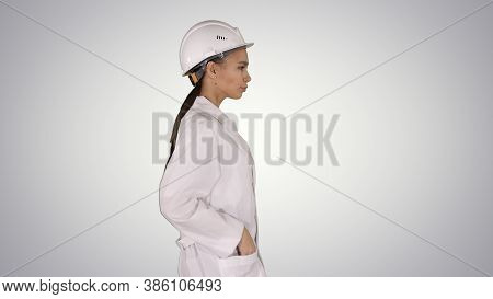 Woman In White Robe Putting Hard Hat On While Walking On Gradien