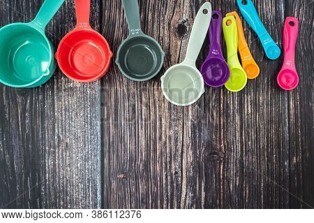 Set Of Colorful Measuring Cups And Measuring Spoons Use In Cooking Lay On Dark Brown Wood Tabletop I