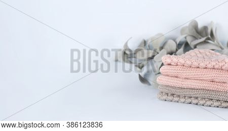 Pile Of Pink Knitted Cashmere Scarves, Sweaters On Light Blue Background. Folded Autumn And Winter C