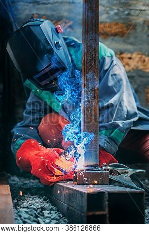 A Welder Welds A Metal Pole With Electric Welding, Holds An Electrode In His Hands, Selective Focus