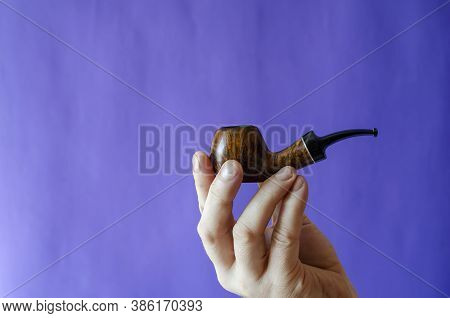 Briar Root Smoking Pipe In Hand. A Mans Hand Holds A Classic Smoking Pipe On A Blue Background. Sele