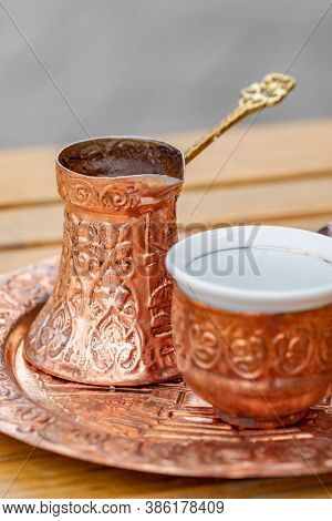 Traditional black bosnian coffee in beautiful copper cezve at wooden table. A complete Bosnian coffee set is called a kahveni takum