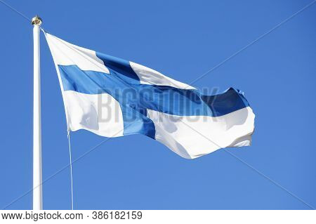 The Flag Of Finland Waves In The Wind Against The Blue Summer Sky