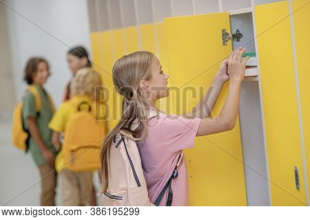 Pretty Girl In Pink Tshirt Putting Books To Her Locker