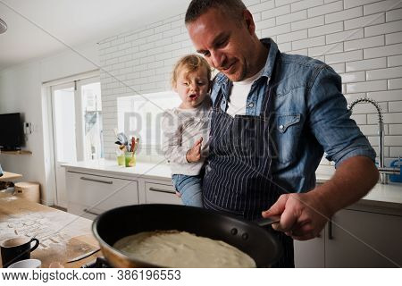 Father And Daughter Cooking Batter In Pan Standing In Modern Kitchen.