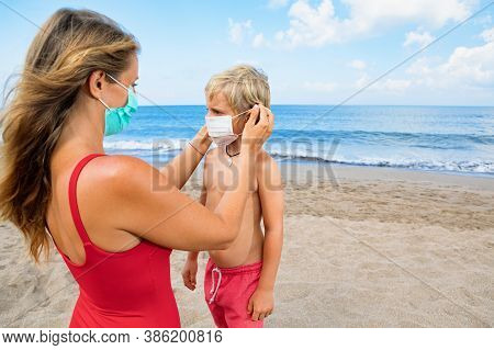 Mother Put Medical Mask On Child On Sea Beach. New Rules To Wear Cloth Face Covering At Public Place