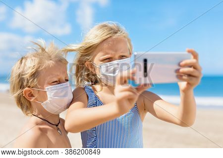 Funny Kids Taking Selfie Photo By Smartphone On Tropical Sea Beach. New Rules To Wear Cloth Face Cov