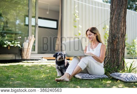 Mature Woman Working In Home Office Outdoors In Garden, Using Laptop.