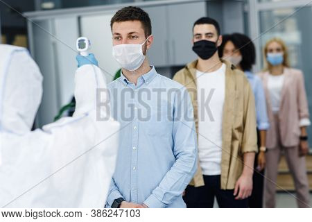 Preventive Measures To Protect Against Virus Outbreak. Man In Protective Suit Measures Temperature O