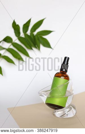 Close Up Glass Bottle Wirth Cosmetic Product And Green Space For Brand Near Leaf.