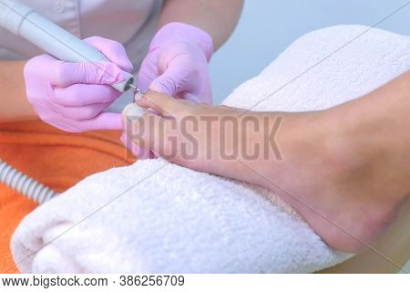 Pedicurist Woman Removes Cuticle From Clients Toes Using Electric Nail Machine, Closeup View. Profes