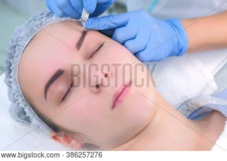 Beautician Is Painting Shaping Contour Using Manual Tool For Tattoo, Womans Face Closeup. Cosmetolog