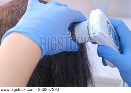 Doctor Trichologist Examines Woman Patients Hairs Using Trichoscope In Clinic, Closeup View. Runs A 