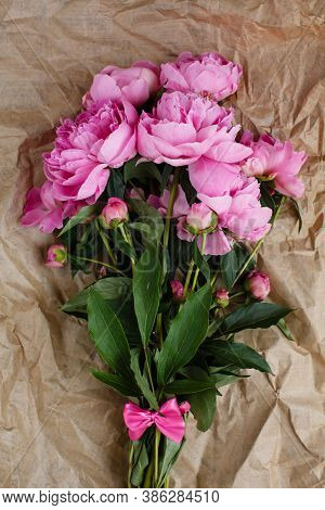 Fluffy Bouquet Of Pink Peonies Flowers In Sunlight On Wrinkled Craft Paper Background, Top View