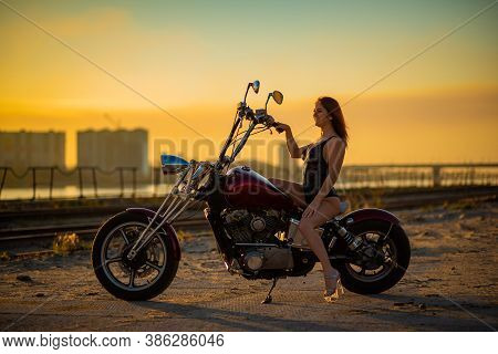 Red-haired Woman In Sexy Lingerie In High Heels Sits On A Motorcycle. Attractive Red-haired Girl Sit