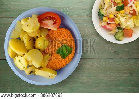 Meatball With Potatoes On Green Wooden Background. Meatball With A Slice Of Tomato On Light Blue Pla