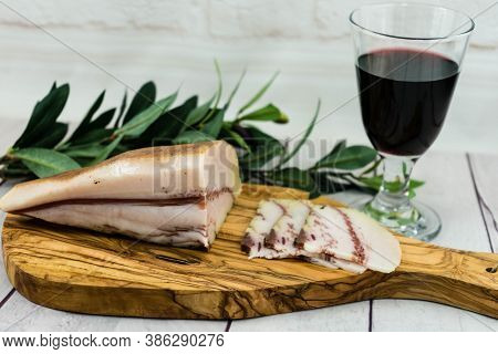 A Piece Of Ham On Olivewood With A Glas Of Redwine