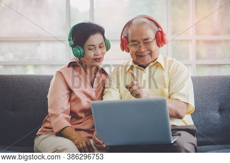 Happy Elderly Couple Is Watiching And Listening To Music Movie From Laptop Computer With Colorful He