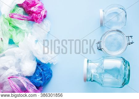 Many Disposable Plastic Bags Vs Reusable Glass Jars On A Blue Background. Zero Waste Shopping. Susta
