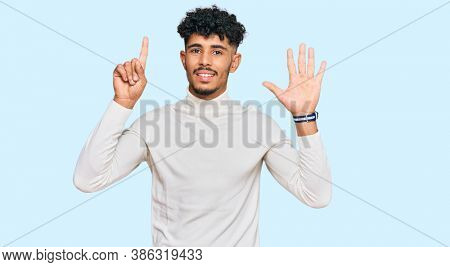 Young arab man wearing casual winter sweater showing and pointing up with fingers number six while smiling confident and happy. 
