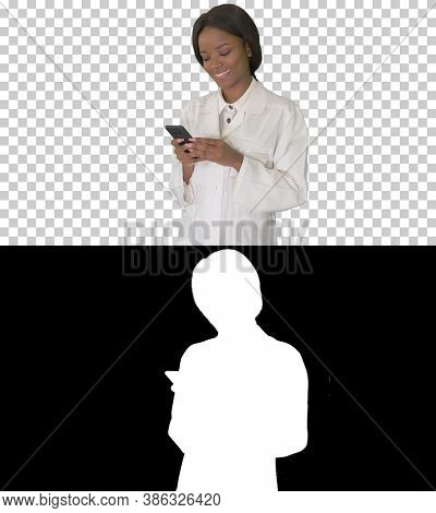Smiling African American Female Doctor Texting Message On Smartp