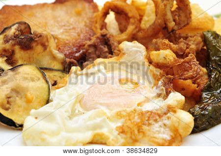 Nærbillede af et spansk combo fad med spejlæg, grillet peber, stegte calamares, paneret tenderlo