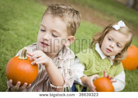 Søde unge bror og søster børn nyder græskar på den Pumpkin Patch.