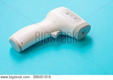 Surface Infrared Thermometer Is Lying On Blue Background. Medical Device For Temperature Measurement