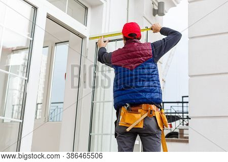 A Worker Installs Panels Beige Siding On The Facade Of The House