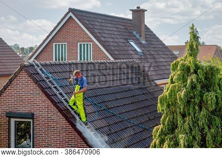 Urk, The Netherlands - September 15, 2020: Cleaner With Pressure Washer At Roof Of House Cleaning Th