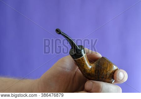 Briar Root Smoking Pipe In Hand. A Mans Hand Holds A Classic Smoking Pipe On A Blue Background. Sele
