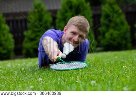 Close Up Male Badminton Player With Racket In Action. Young Concentrated Man Playing Badminton Outdo