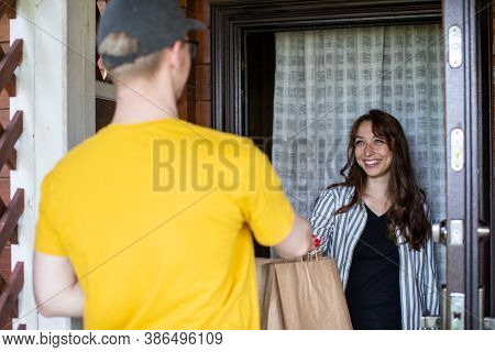 Delivery Man In Yellow T-shirt Handing Paper Bags To Happy Recipient, Beautiful Woman Customer Recei