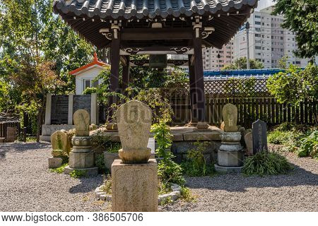 Geumsan, South Korea; September 12, 2020: Reliefs Of Monk Carved In Rocks Surround Wooden Bell Pavil