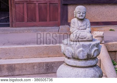Geumsan, South Korea; September 12, 2020: Small Seated Buddha On Ornamental Plinth In Front Of Build