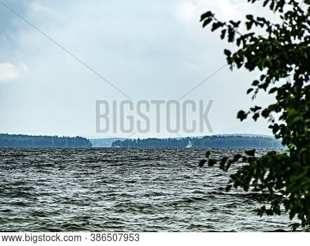 View Of The Forest Lake With A White Sail In The Distance, Lake Uvildy