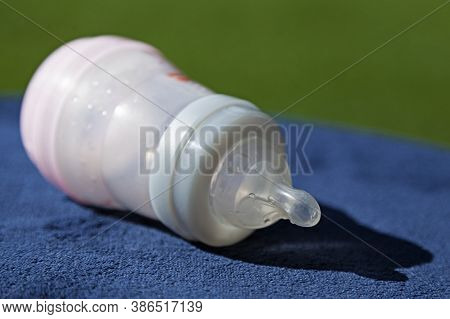 A Baby Bottle Lying On A Blue Tablecloth