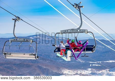 Fun Team Of Friends Skier And Snowboarders Up Ski Lift On Blue Sky Background