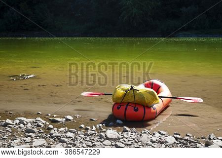 Orange packraft rubber boat with backpack on a river. Packrafting. Active lifestile concept