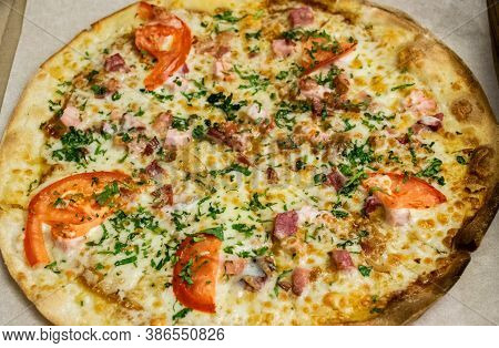 Round Pizza With Ham, Cheese, Tomatoes And Herbs And Bacon In A Cardboard Box. Fast Food Delivery.