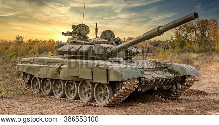 A Side Shot Of Russian Tank T-64 In The Field. Beautiful Sunset Sky As A Background.