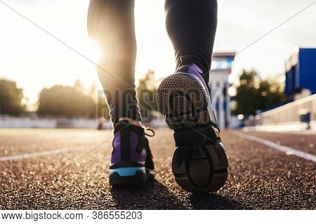 Runner Feet Running On Stadium Tracks Closeup On Shoe. Woman Fitness Sunset Jog Workout Welness Conc