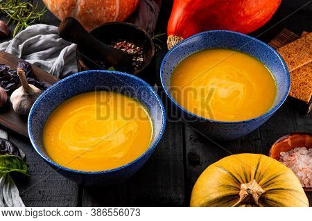 Two Bowls Of Hot Pumpkin Soup On A Black Wooden Table Close Up