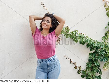 Young Women Wearing T-shirt And Jeans Stays Near A Wall And Smile