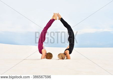 Two Beautiful Young Women Doing Stand On The Forearms Together On The Beach