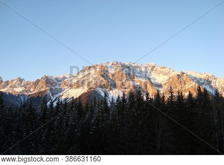 Landscape With Snowy Mountains And Forest Against A Blue Sky
