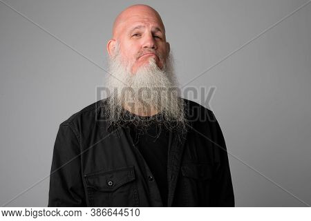Face Of Mature Bald Man With Long Beard Making Smug Expression