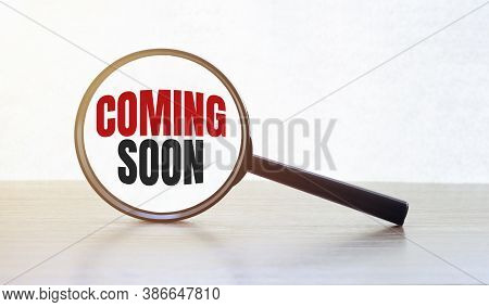 Magnifying Glass With Text Coming Soon On Wooden Table.